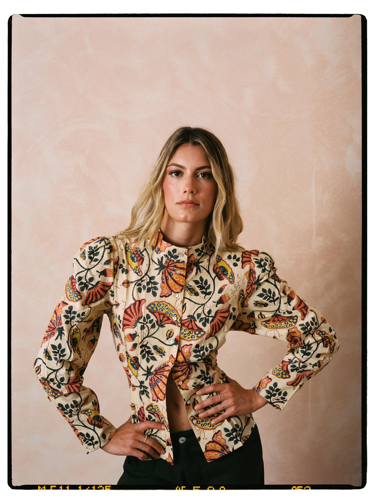 Beige floral-and-butterfly print long-sleeve button-up shirt worn with black pants