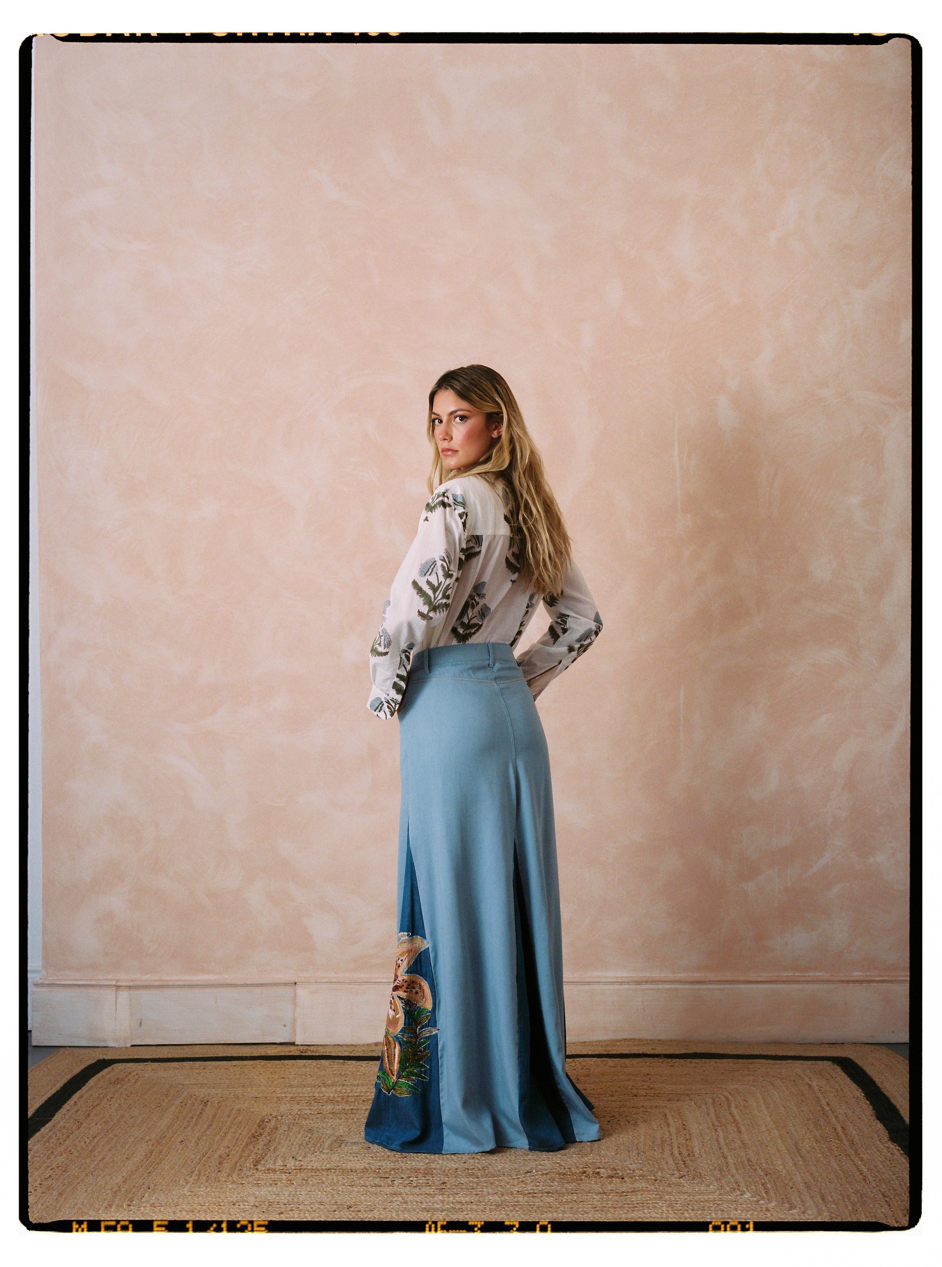 Light blue denim maxi skirt with front slit and multicolor floral embroidery at side hem