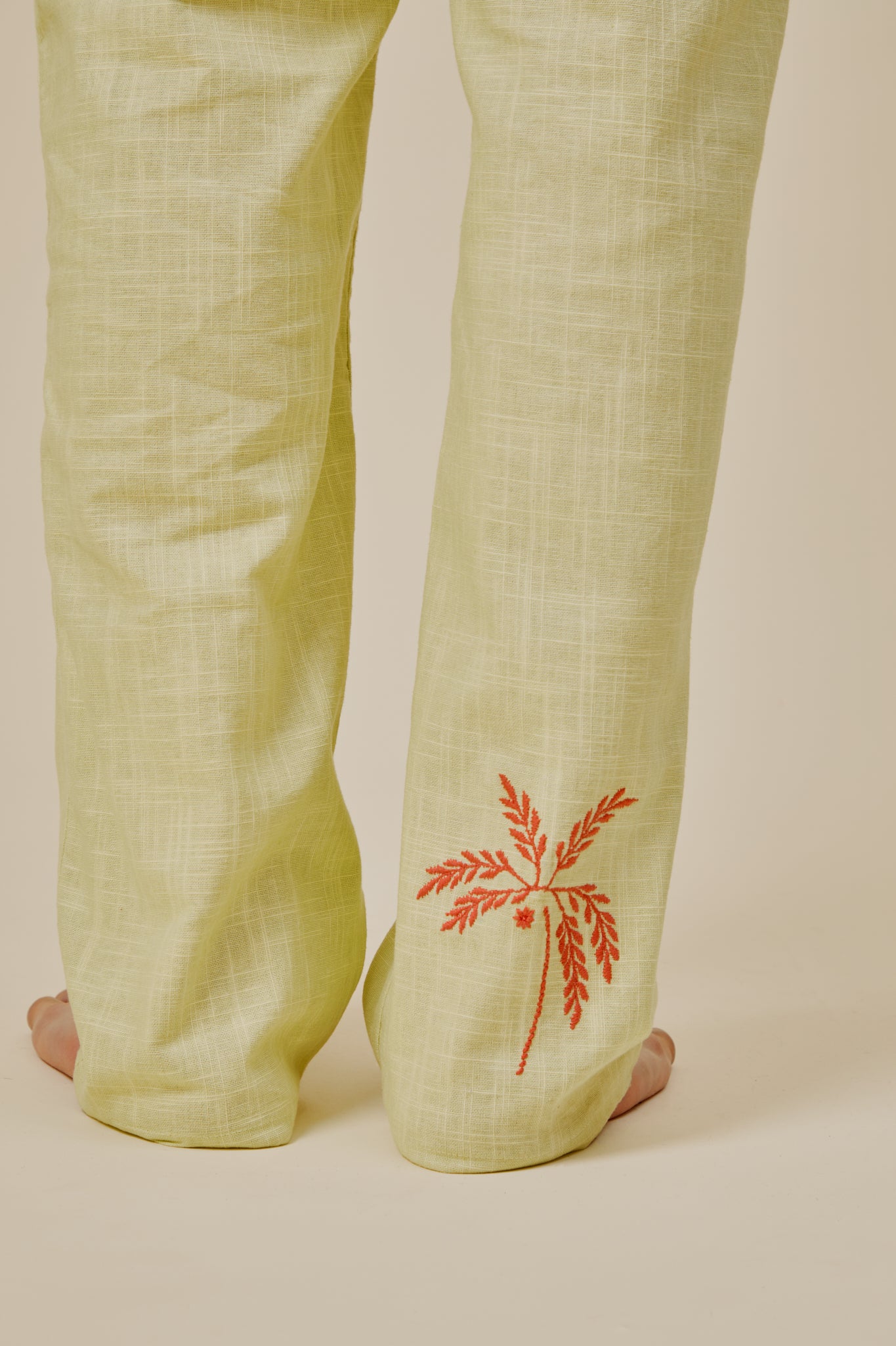 Cecil trousers hem with red embroidered leaf motif on light yellow fabric