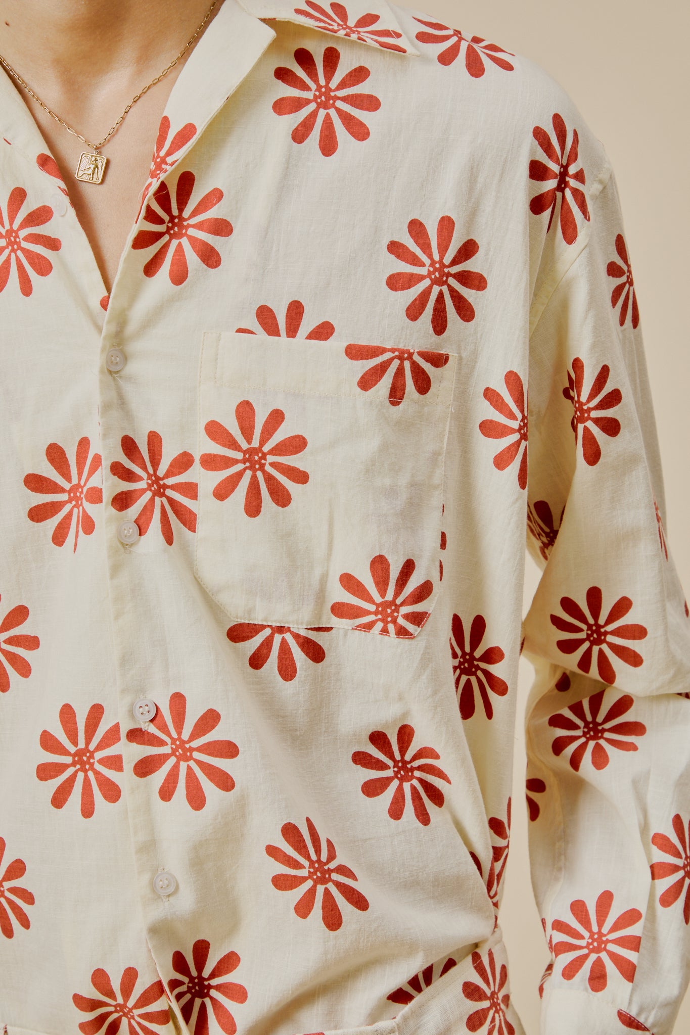 Cream button-up shirt close-up with red flower burst print and buttoned front placket