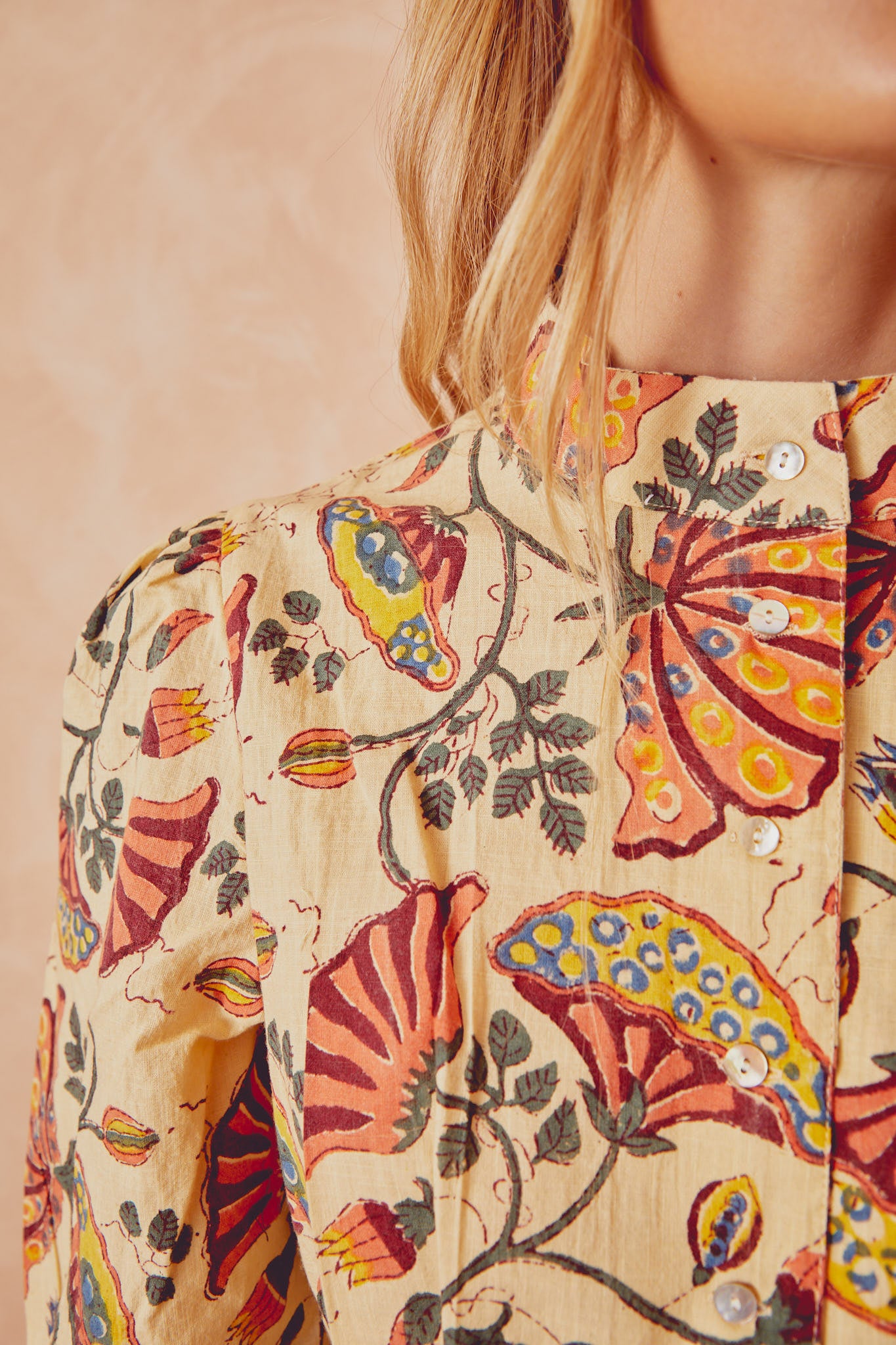 Beige patterned button-up shirt with rounded collar and small white buttons