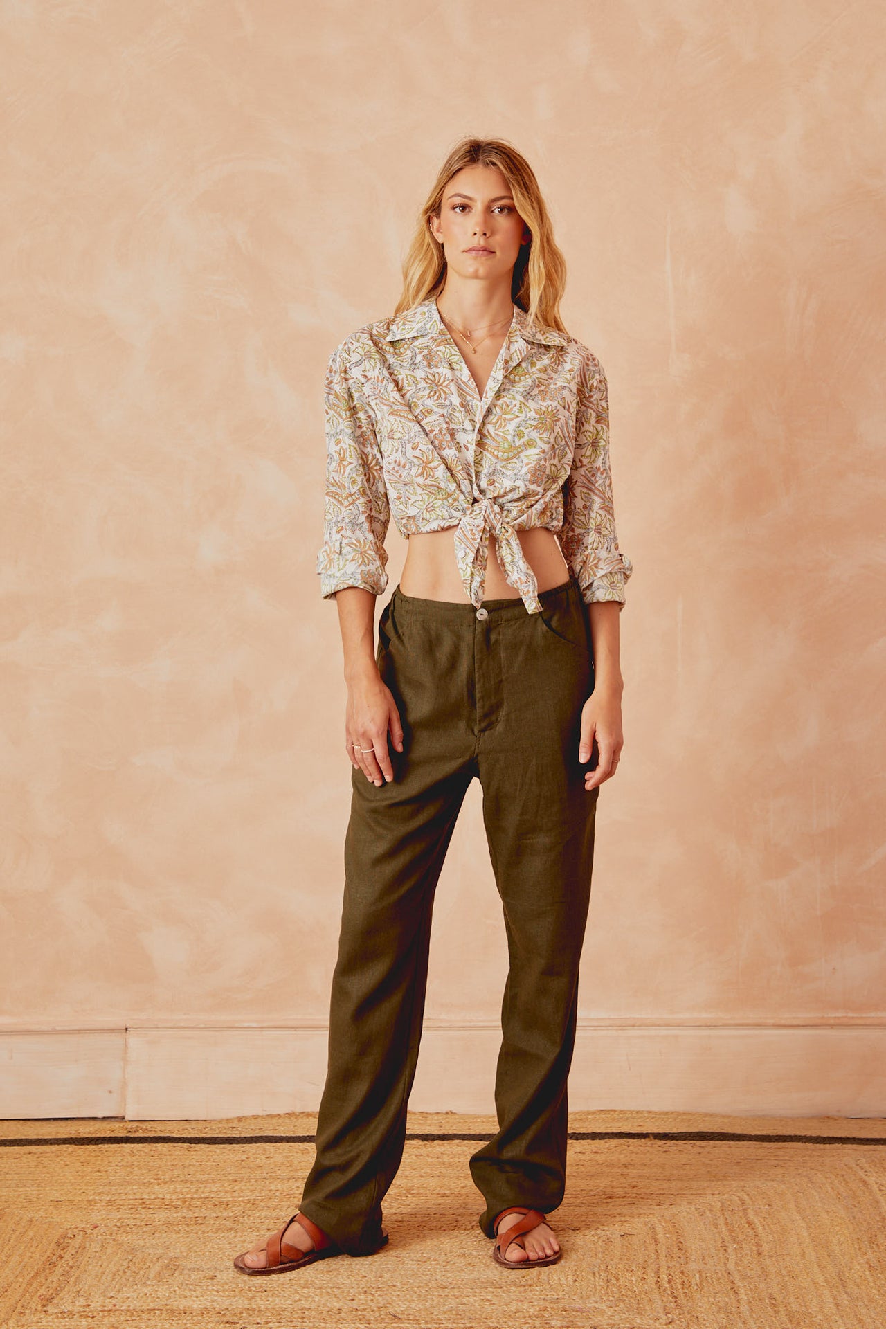 Dark green trousers with button waistband and loose wide-leg fit.