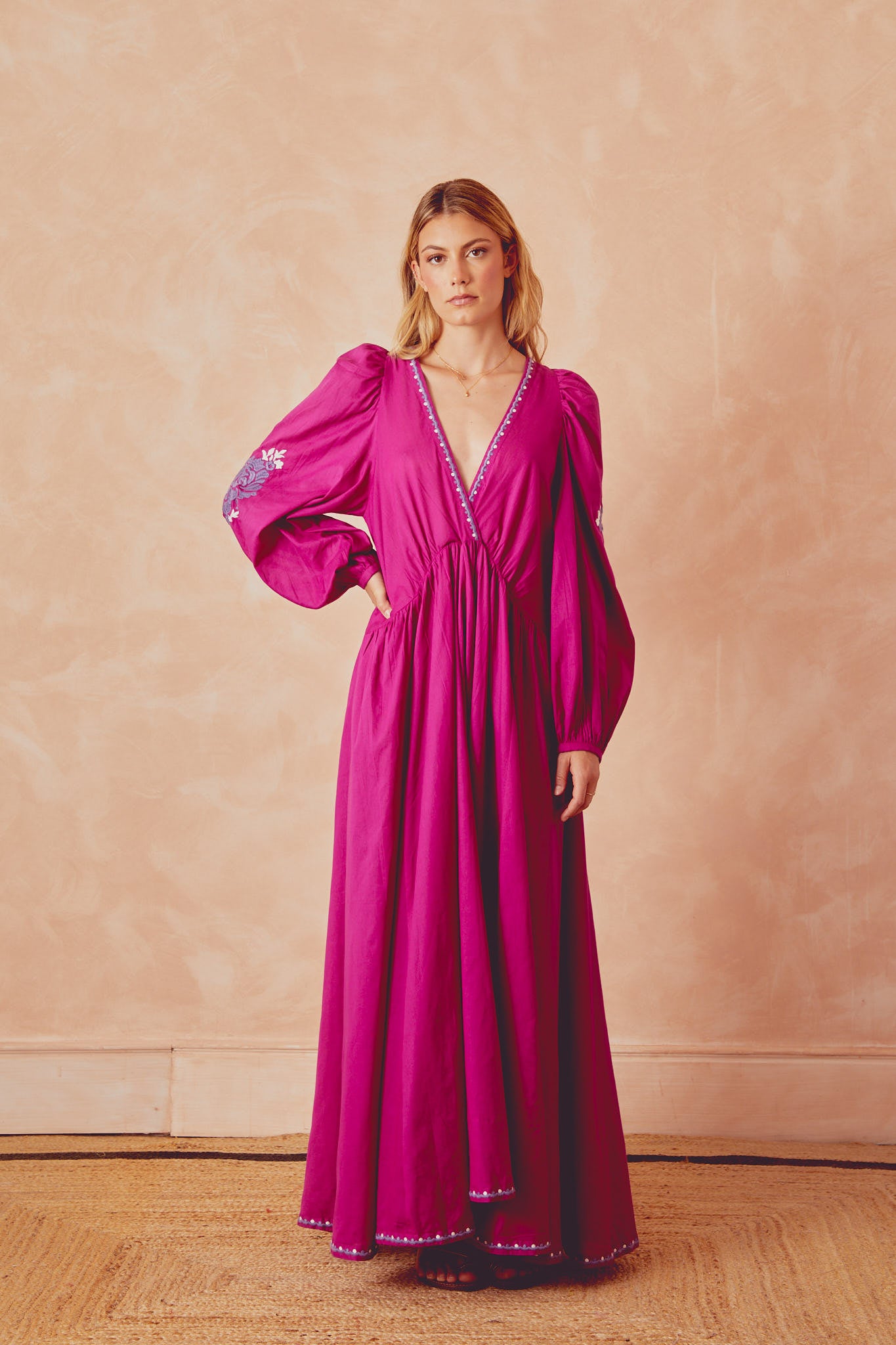 Magenta long dress with V-neck edging, puff sleeves, and embroidered border at hem