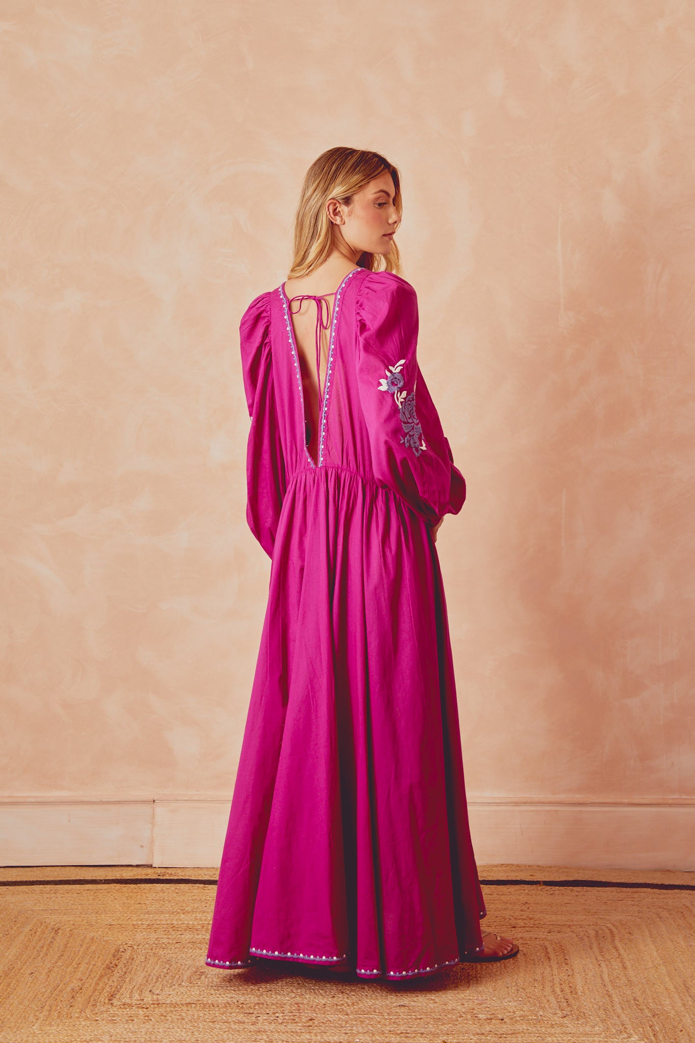 Side view of magenta long Isla dress with open back tie and embroidered sleeve motifs
