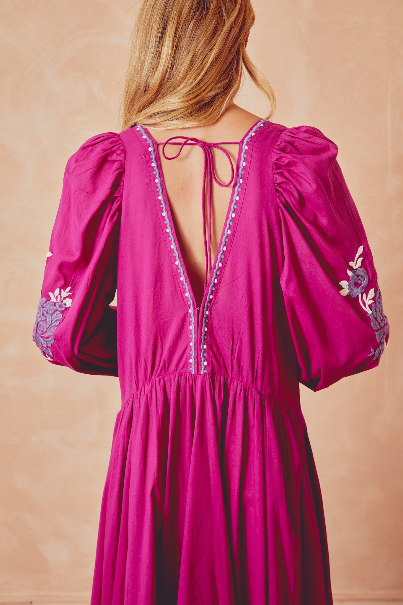 Back view of magenta long dress with embroidered shoulder detailing and open V back