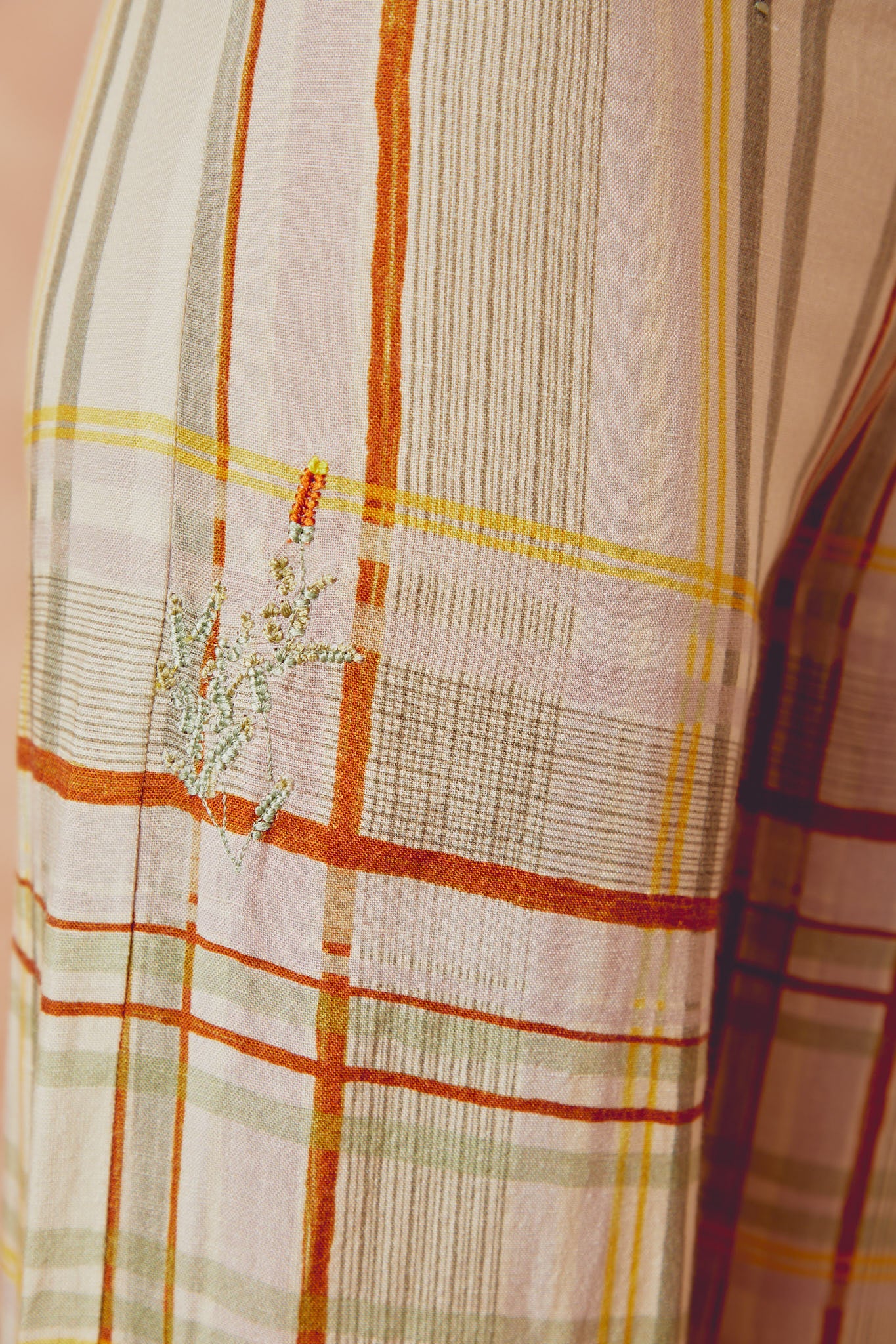 Embroidered plaid trouser fabric panel with orange, yellow, and white thread details