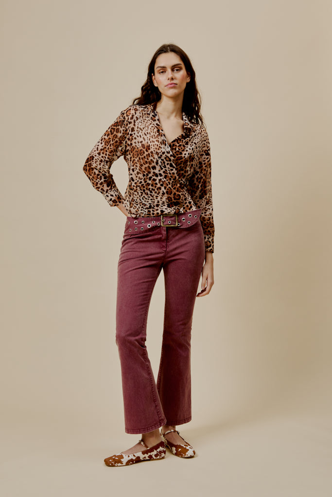 Burgundy flared trousers with studded belt and straight-to-flare leg silhouette