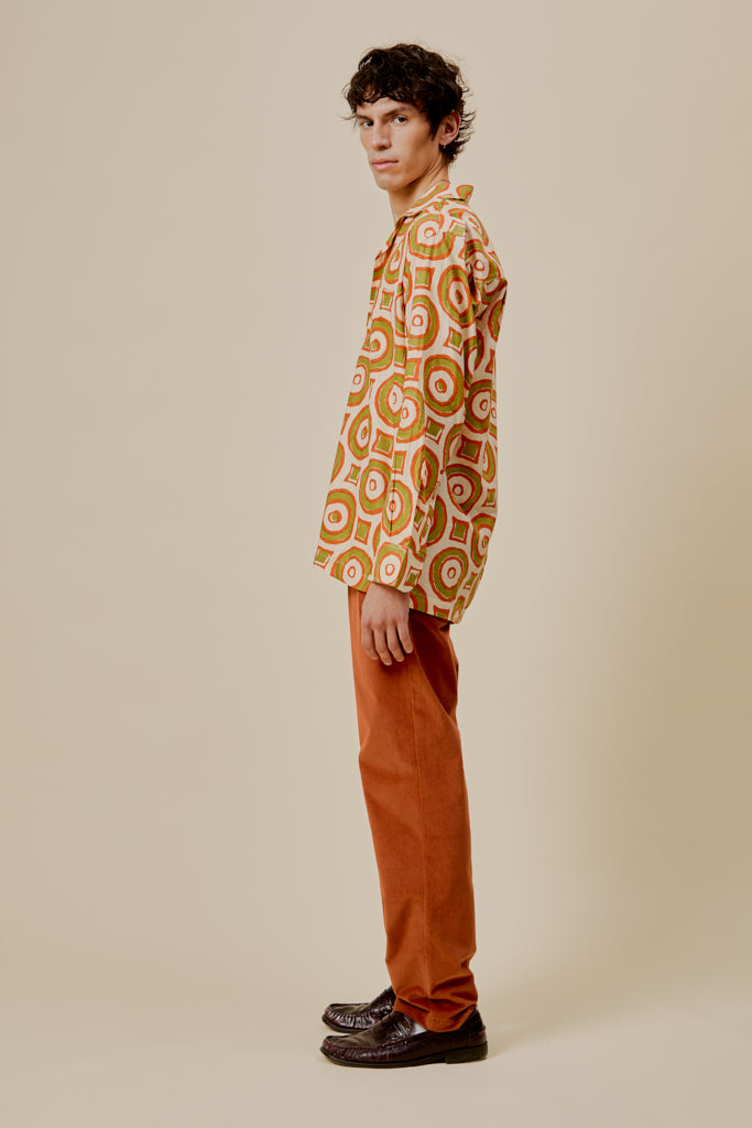 Orange button-up shirt with circular print, long sleeves, side profile