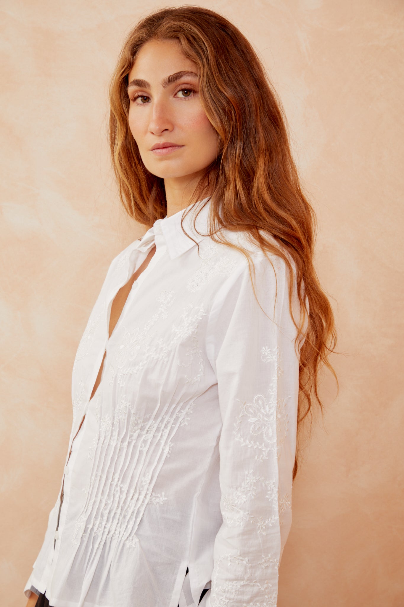 White button-up shirt with open collar and vertical embroidered floral design.