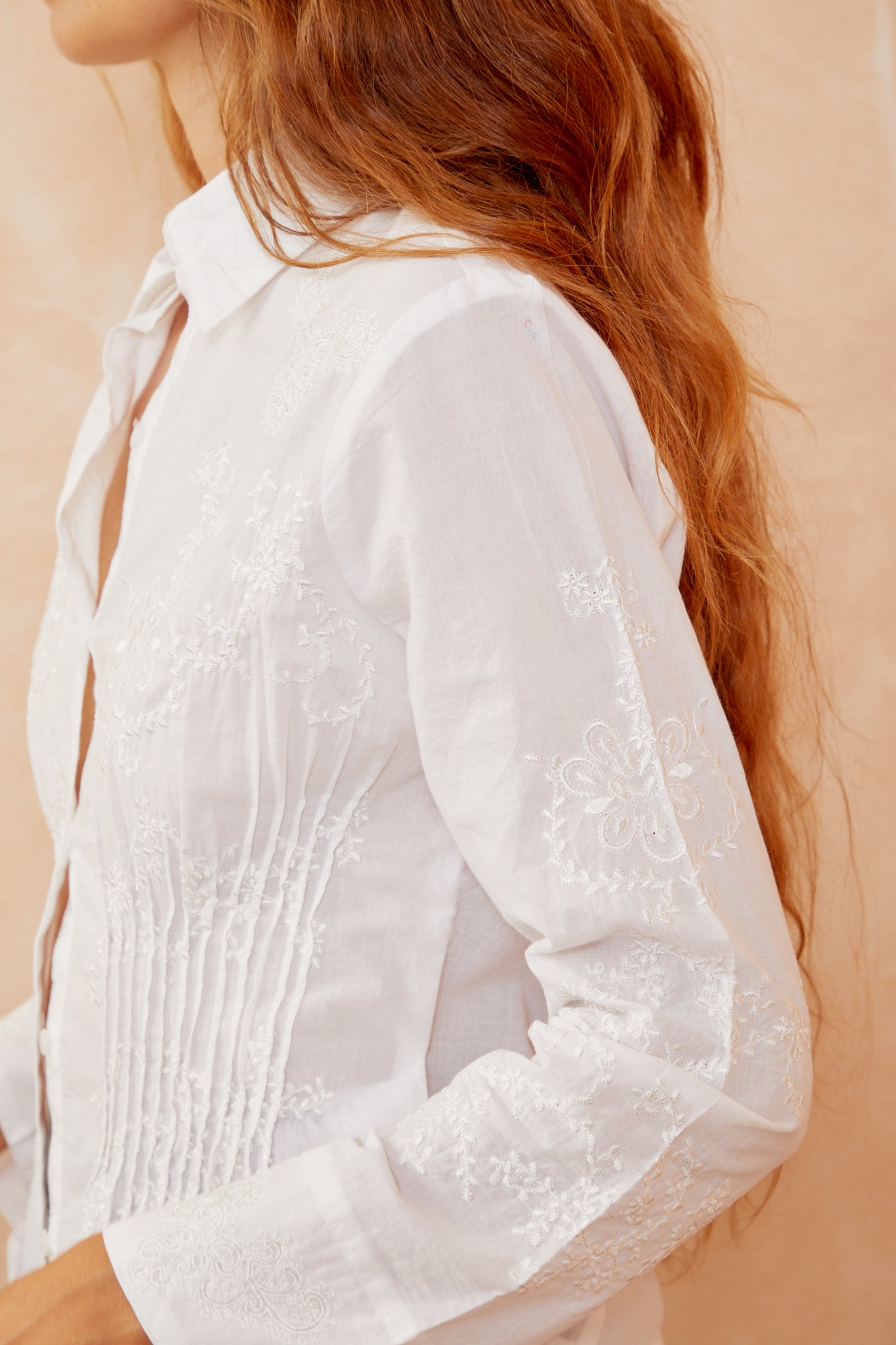 White shirt sleeve and back yoke detail with embroidered floral pattern.