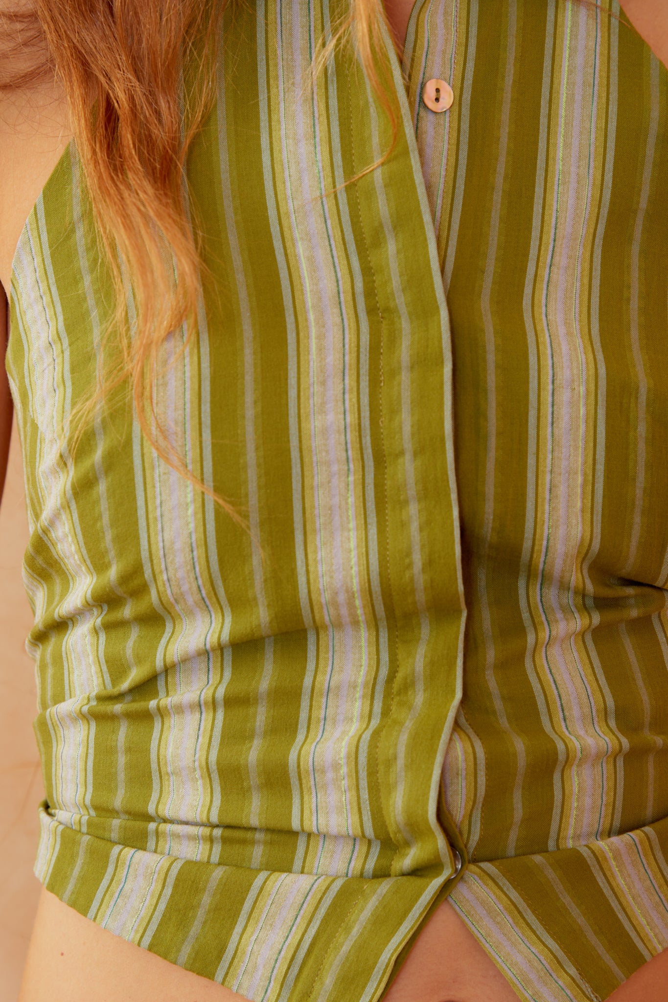 Green-striped sleeveless top close-up with button placket and pointed collar