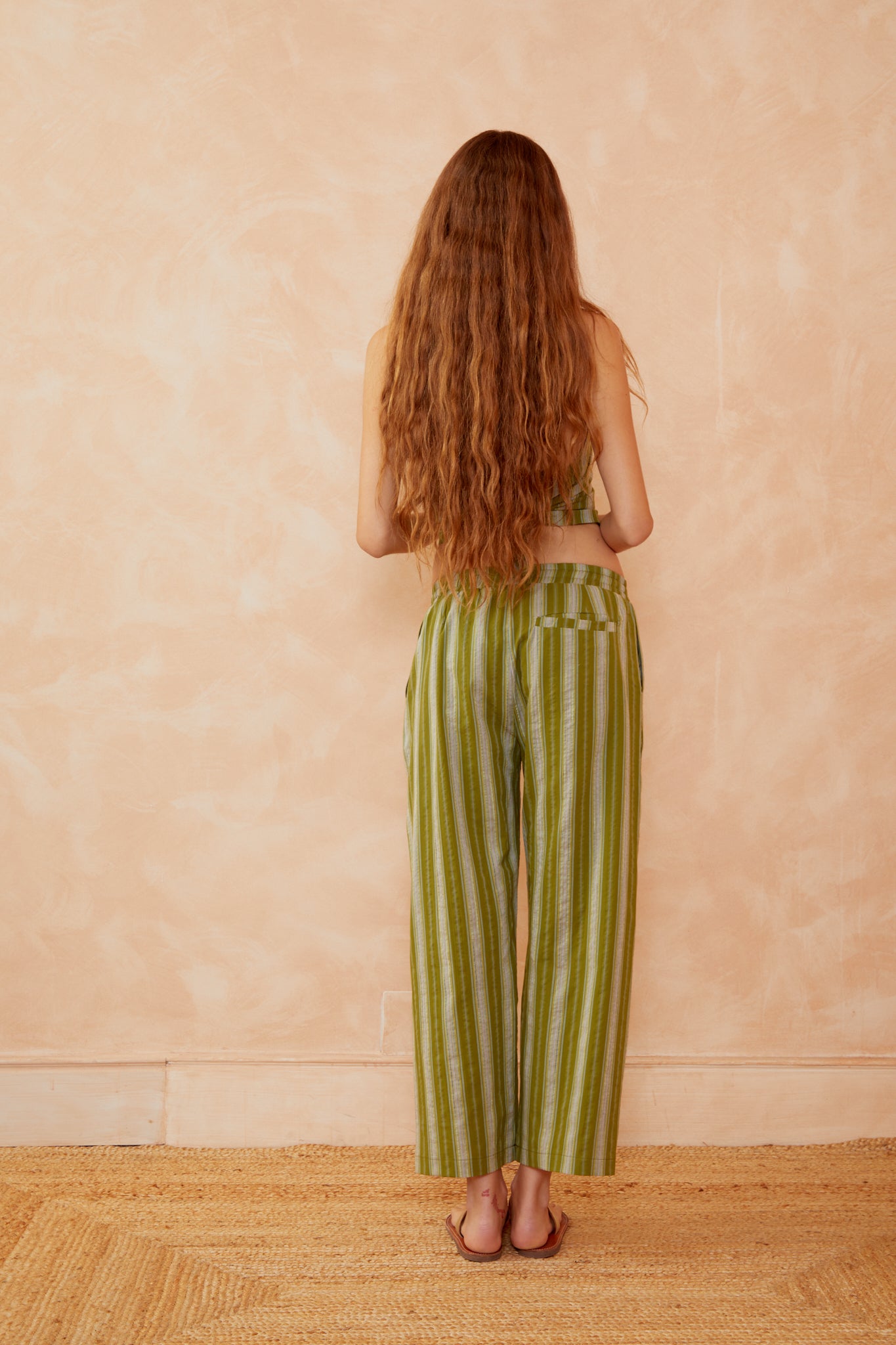 Pantalones anchos rayados de verde y amarillo, vista posterior, con cordón en la cintura y lazo