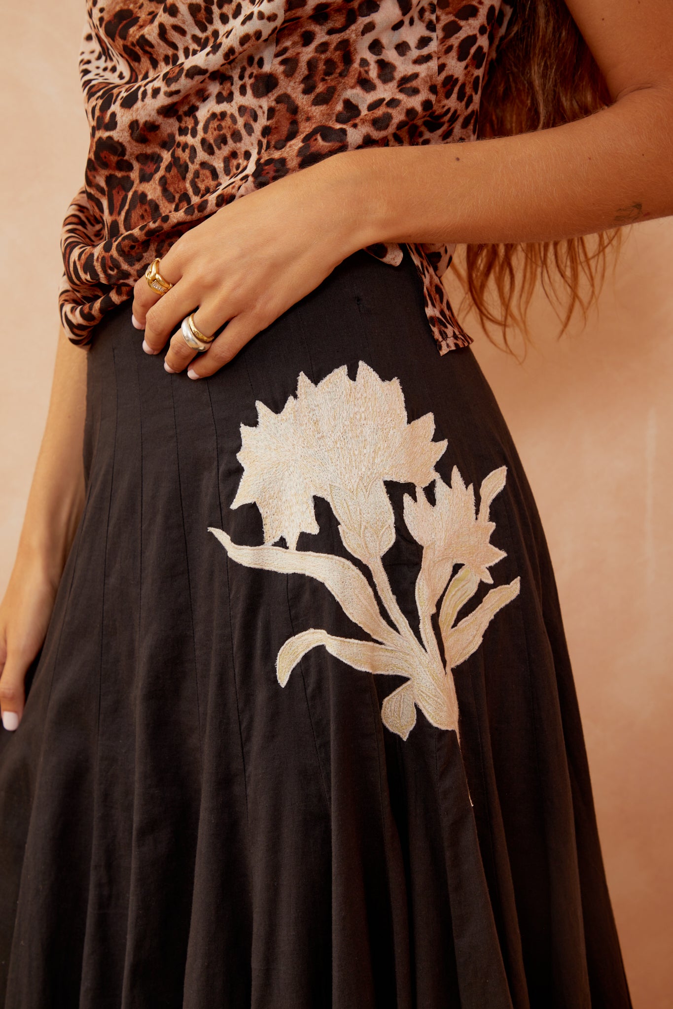 Black skirt with large white floral/leaf applique and pleated texture