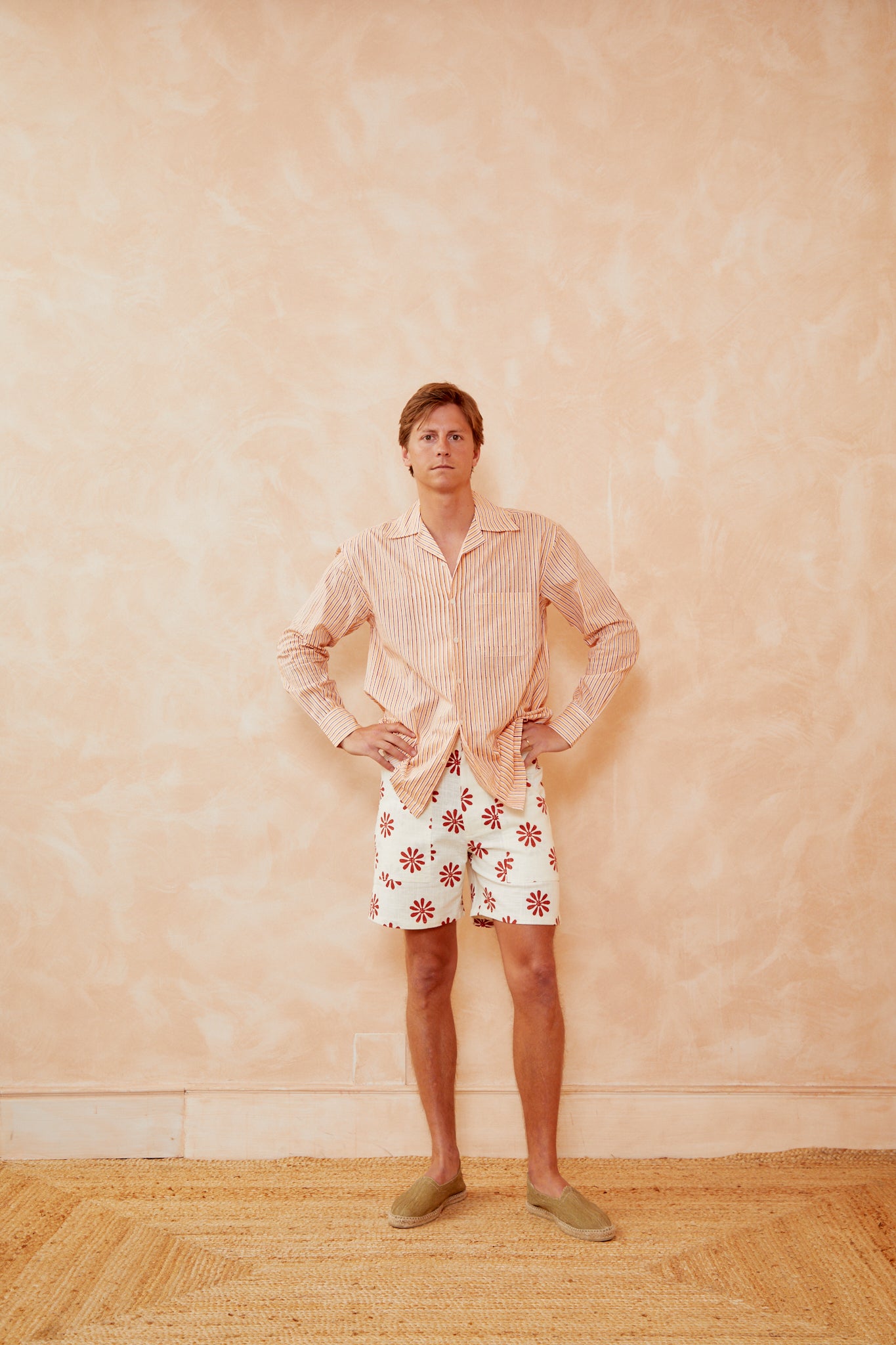 Floral bermuda shorts on white with red daisy-like flower print, above-knee