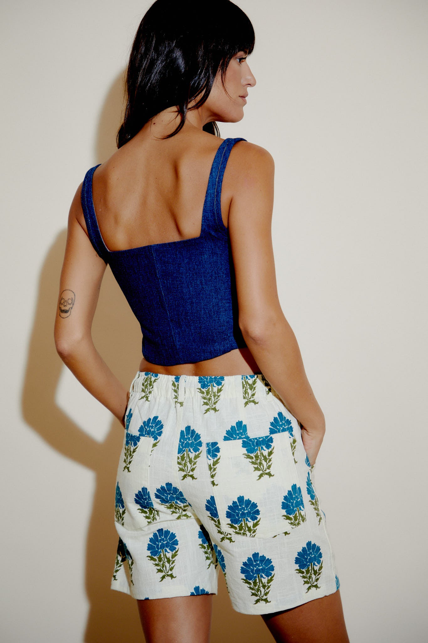 Cream floral bermuda shorts with blue flowers, side/back view, above-knee length