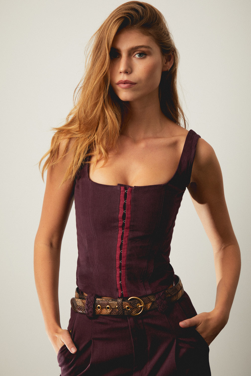 Aubergine corset with square neckline, vertical front panels, and red button lacing