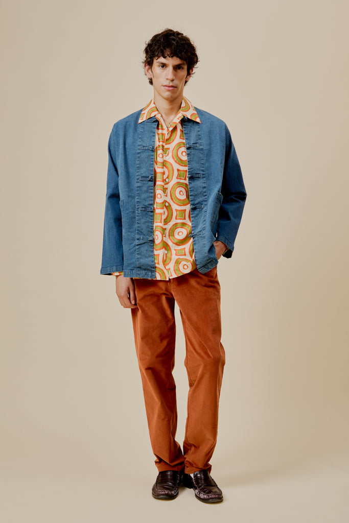 Orange trousers on model, relaxed fit with front button closure and pockets