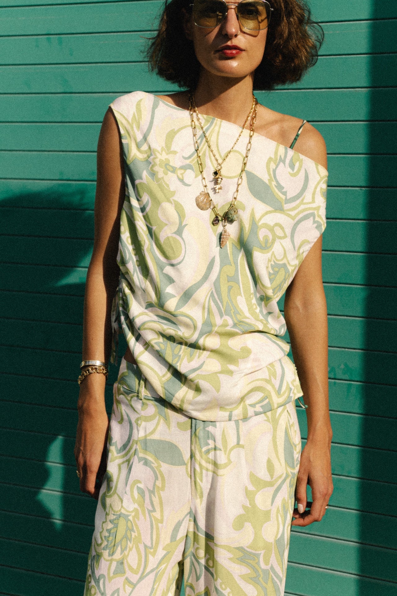 Sleeveless cowl-neck top in white with green leaf print, knotted side ties