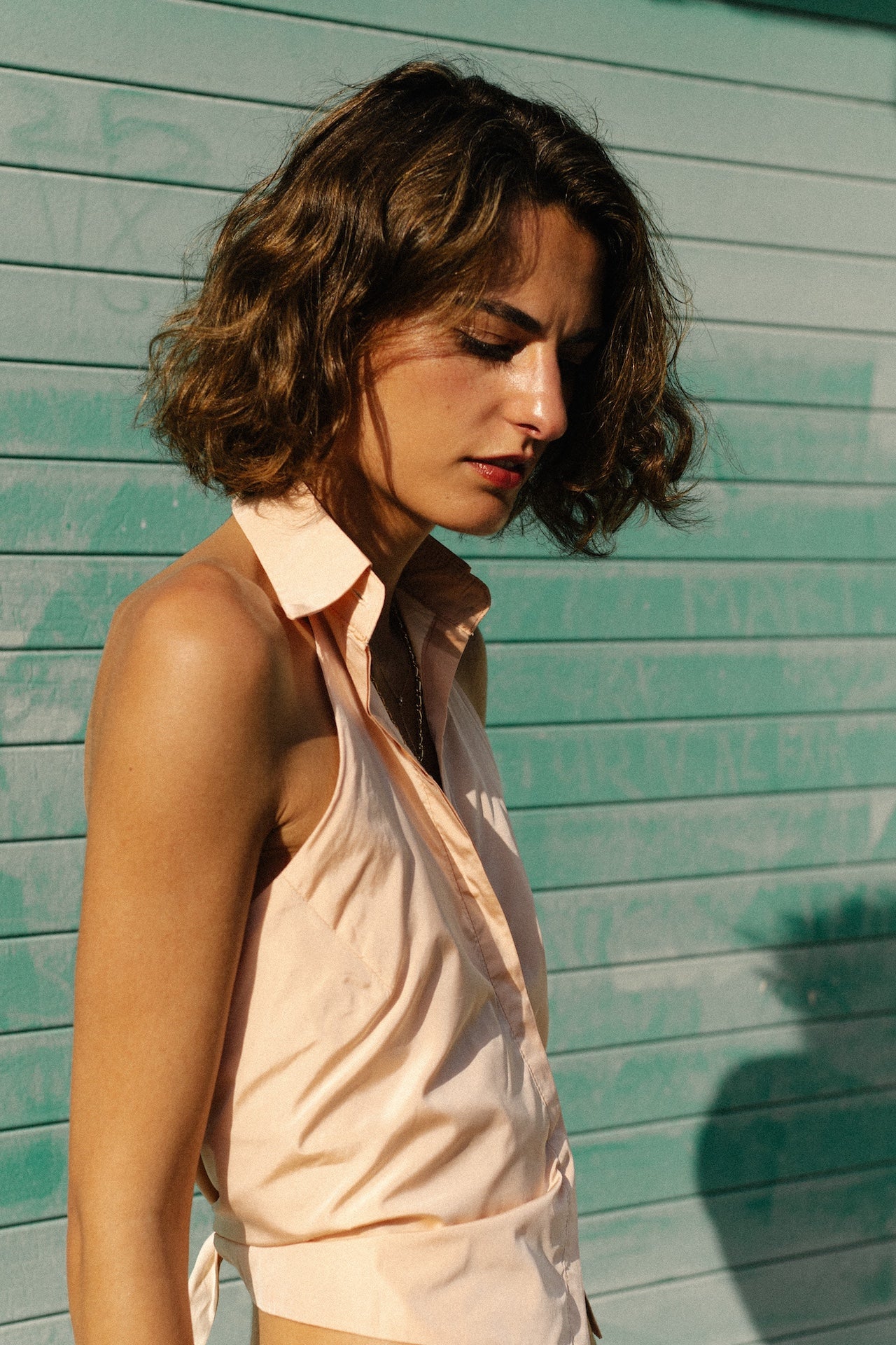 Sleeveless pink button-up top with pointed collar, side view